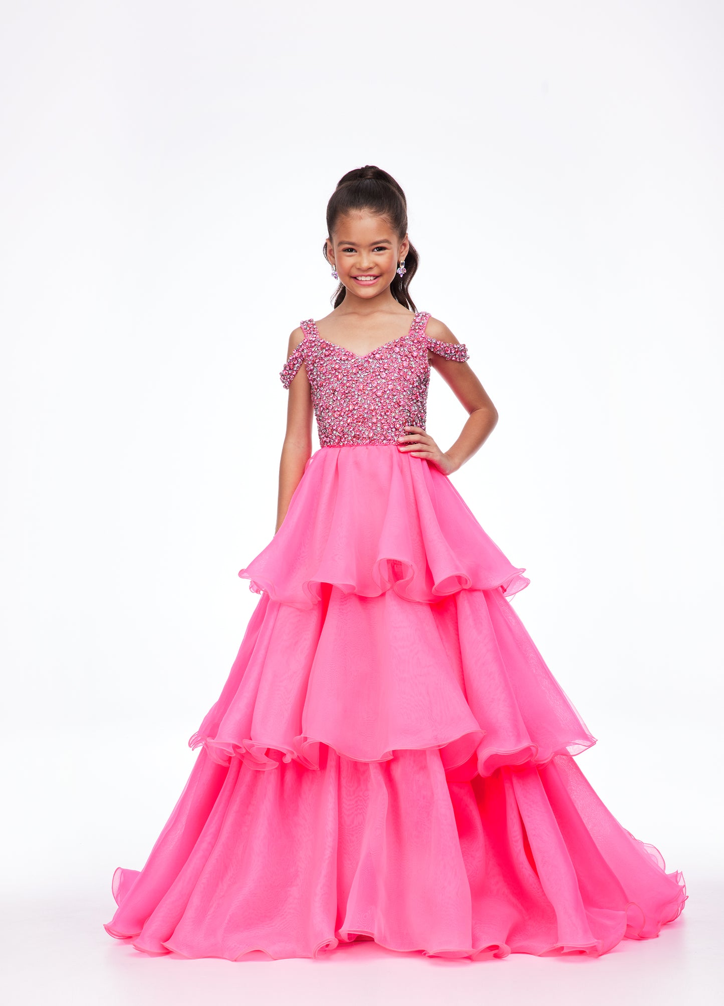Ashley Lauren Kids 8101 Girls Pageant Dress.  The crystal encrusted bodice on this kids Pageant Gown consists of a slight V-Neckline and off the shoulder straps. The A Line multi-tiered organza ruffle skirt completes the look with a long train.   Available colors:  Hot Pink, Lilac, Turquoise