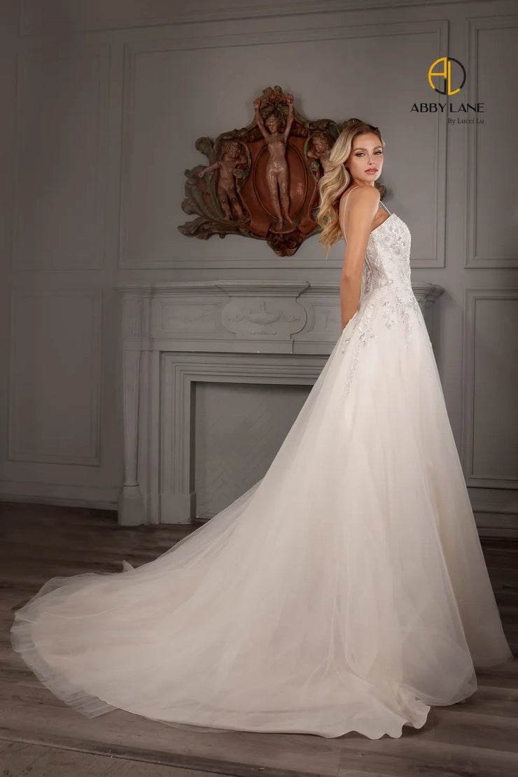Abby Lane Bridal 97177 is a beautiful Long A Line lace tulle Ballgown featuring a v-neckline, sheer back and a beaded bodice with a sequined embellishment. The waist is accented with a satin belt and features a long train. This stunning gown is perfect for a bridal ceremony.  Sizes: 2-14   Color: Ivory/Champagne