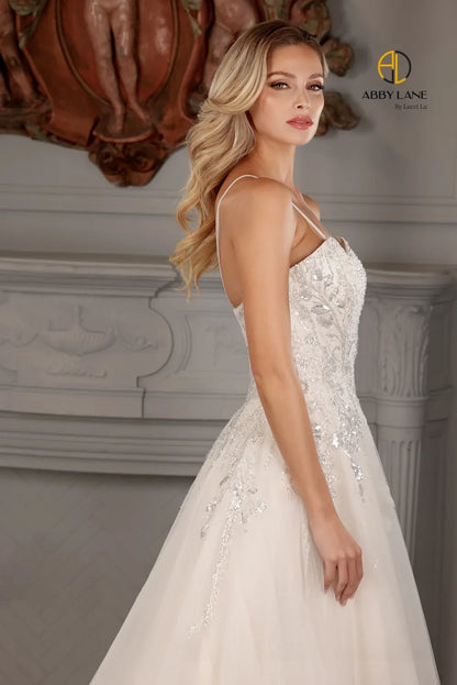 Abby Lane Bridal 97177 is a beautiful Long A Line lace tulle Ballgown featuring a v-neckline, sheer back and a beaded bodice with a sequined embellishment. The waist is accented with a satin belt and features a long train. This stunning gown is perfect for a bridal ceremony.  Sizes: 2-14   Color: Ivory/Champagne