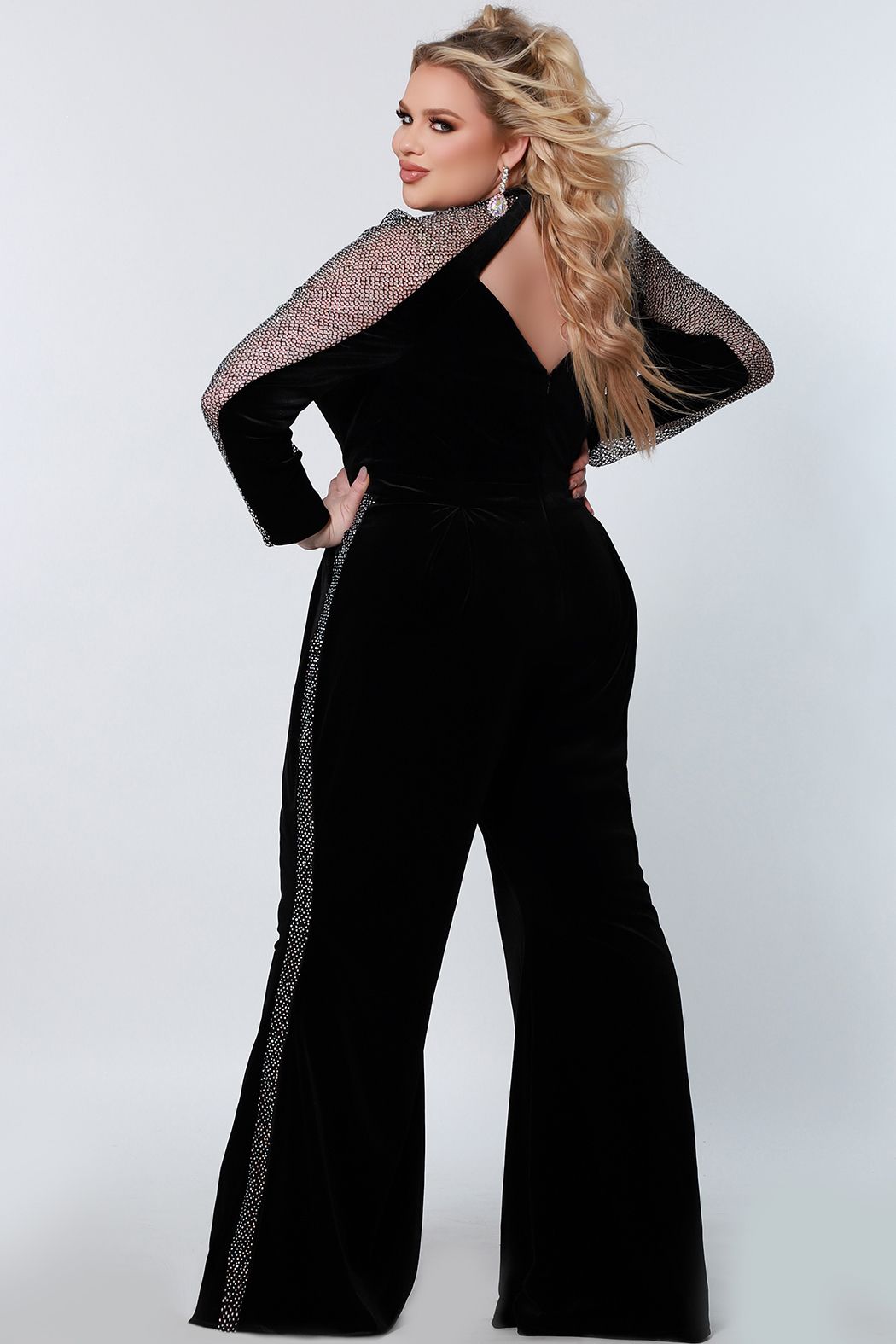 Johnathan Kayne by Sydney's Closet JK2207 You're ready to rock in the hottest jumpsuit of the season! In shade black Caviar, this jumpsuit is a combination of black stretch velvet and stretch crystal mesh that shines without fail. The structure makes all the difference with boning, point pleats through the midsection, and bell bottom pants. Details like the diamond cutout back and crystal mesh tuxedo stripe have you ready to slay your night. JK 2207