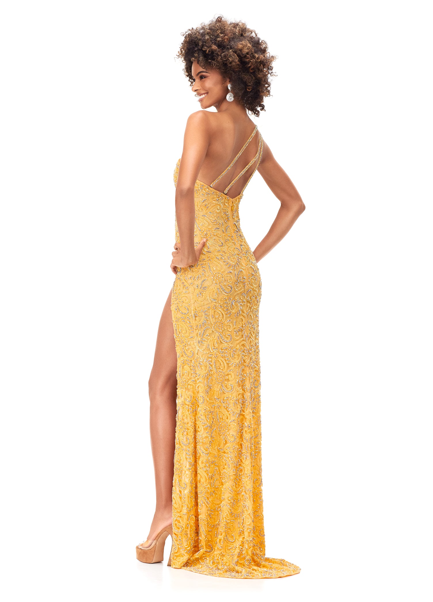 Ashley Lauren 11277 We are obsessing over this gown! This gorgeous one shoulder gown features crystals and beading throughout the bodice and carries onto the skirt. The one shoulder neckline is accented with feathers. The look is complete with a left leg slit and strappy open back. One Shoulder Intricate Sequin & Crystal Beading Left Leg Slit yellow