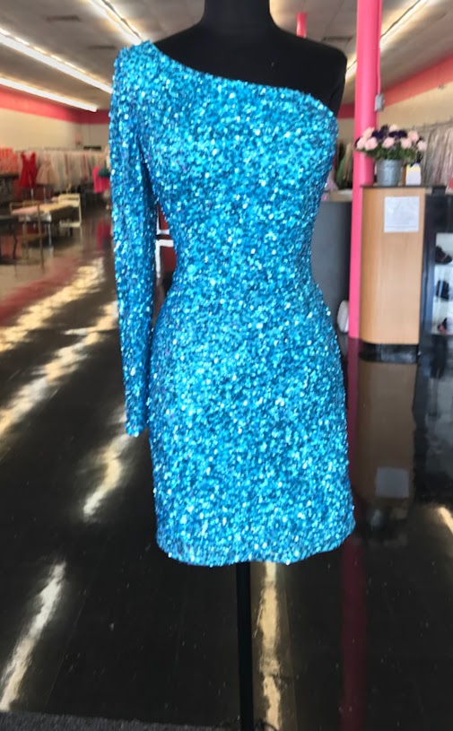 Ashley Lauren 4457 Cocktail Dress.  This is a perfect homecoming or pageant dress, pick your color.  The fitted dress is fully hand beaded sequins with one shoulder neckline and a sheer beaded long sleeve. This dress would make an excellent reception dress if you wanted sparkle at your wedding.   Colors:  Neon Blue  Sizes:  8