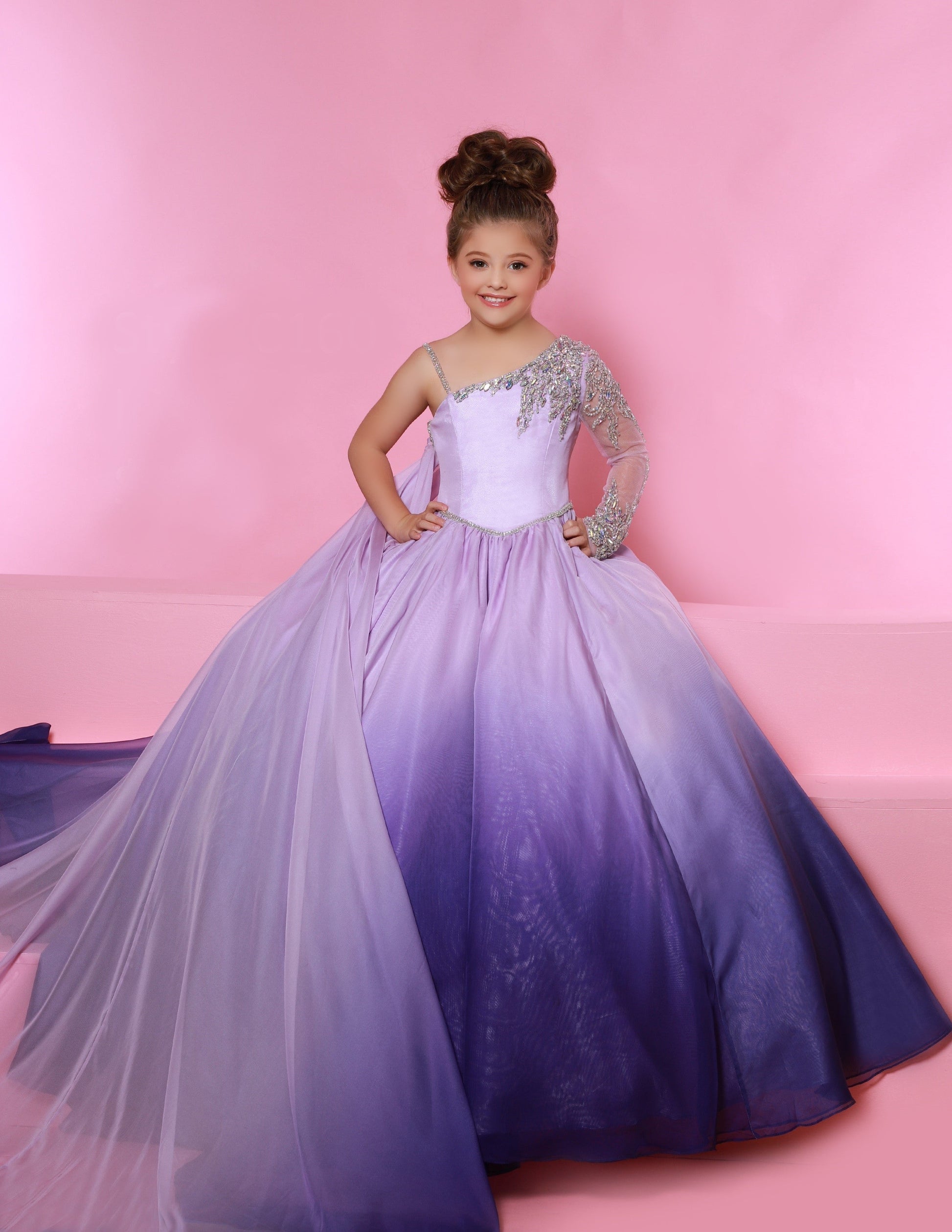 Sugar Kayne C160 is a Girls A Line Ballgown Pageant Dress. Featuring an Ombre Color shift as well as a flowing cape. One shoulder long sleeve with embellishments. embellished waist.  Colors:  Sunset, Iris  Sizes:  2-16  (Sizes 2-6 do not have bust cups, Sizes 8-16 will have preteen size bust cups)