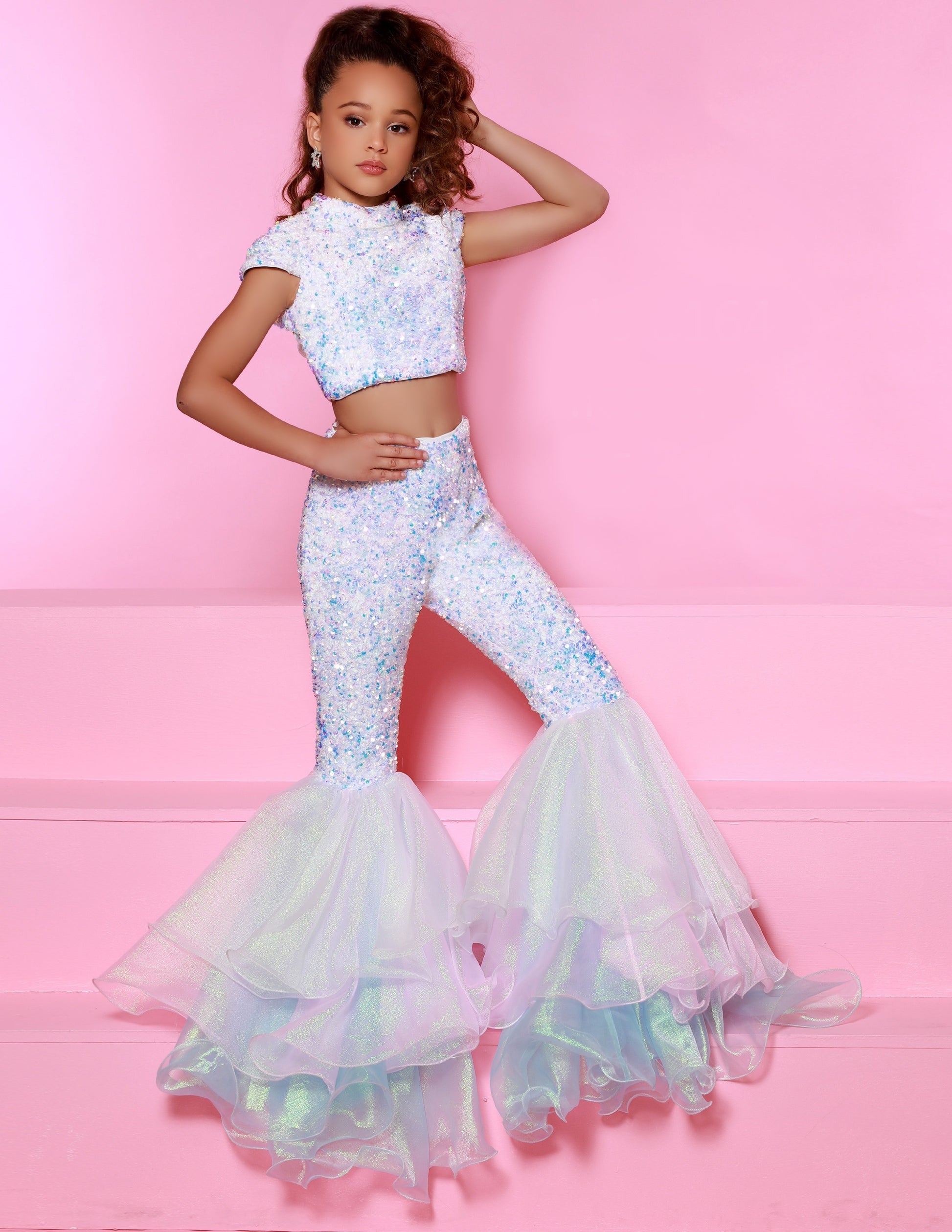 Sugar Kayne C164 This is a two piece girls fun fashion jumpsuit. Featuring Sequin stretch velvet fabric not only is it comfortable but glamorous on stage! high neckline with short sleeves, Backless with an organza bow to tie. Lush Bell Bottoms. Unicorn color features iridescent shimmer organza while royal and red feature regular organza.  Colors: Unicorn, Red, Royal  Sizes:  2-16  (Sizes 2-6 do not have bust cups, Sizes 8-16 will have preteen size bust cups)
