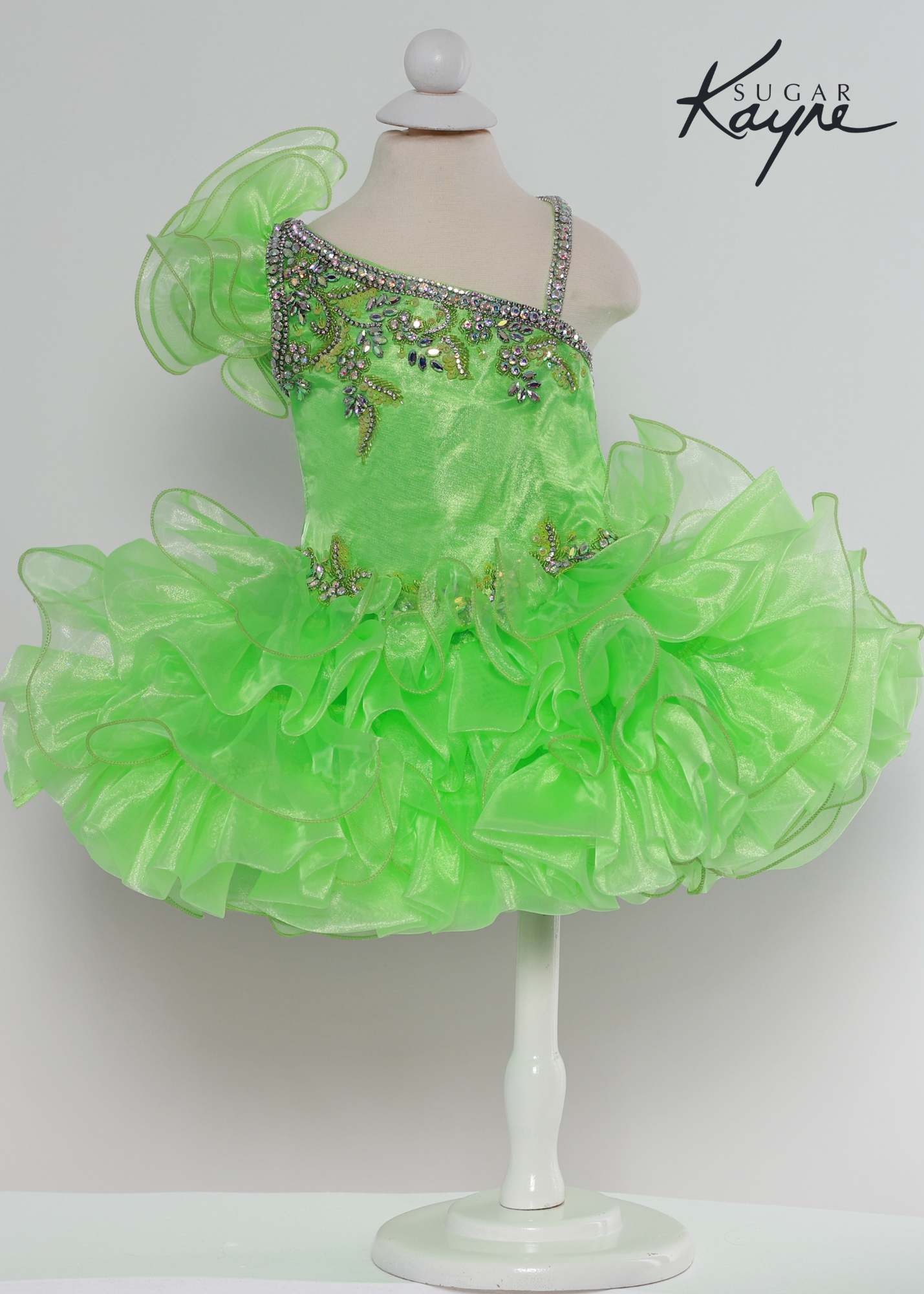 Sugar Kayne C215 Girls Short Cupcake Ruffle One Shoulder Pageant Dress Bow Corset Have your little cupcake bring on all the charm in this stunning organza gown. The corset back is the perfect addition as the little one grows!  Colors: Kiwi, Neon Orange, White  Sizes: 0M, 12M, 18M, 24M, 2T, 3T, 4T, 5T, 6M, 6T  Fabric Organza, Satin Lining
