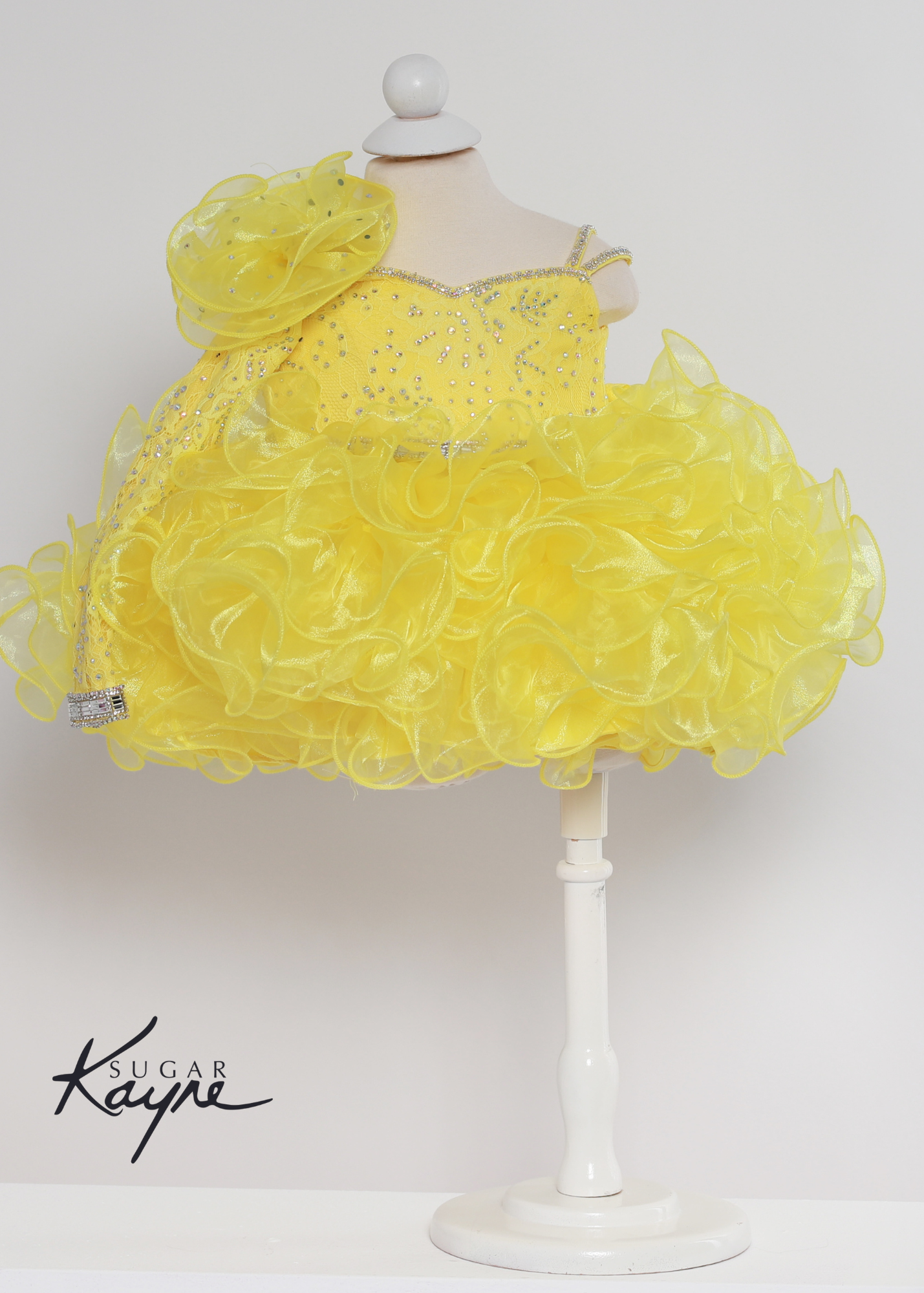 Sugar Kayne C218 Girls Baby Sheer Lace Long Sleeve Cupcake Pageant Dress Crystal Cuff Corset. Have your little cupcake bring on all the charm in this stunning organza and stretch lace gown. The corset back is the perfect addition as the little one grows!  Colors: Baby Pink, Canary Yellow, Electric Blue  Sizes: 0M, 12M, 18M, 24M, 2T, 3T, 4T, 5T, 6M, 6T  Fabric Mesh, Satin Lining