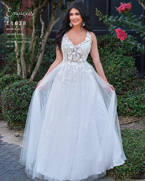 Envious Couture E1628 V neckline prom dress with 3D floral details on the sheer bodice that flow down the glitter tulle ballgown skirt.  This evening gown has a lace up corset tie in the open back. Make a statement at your next formal event, pageant or prom.  Available colors  White  Available sizes  10   