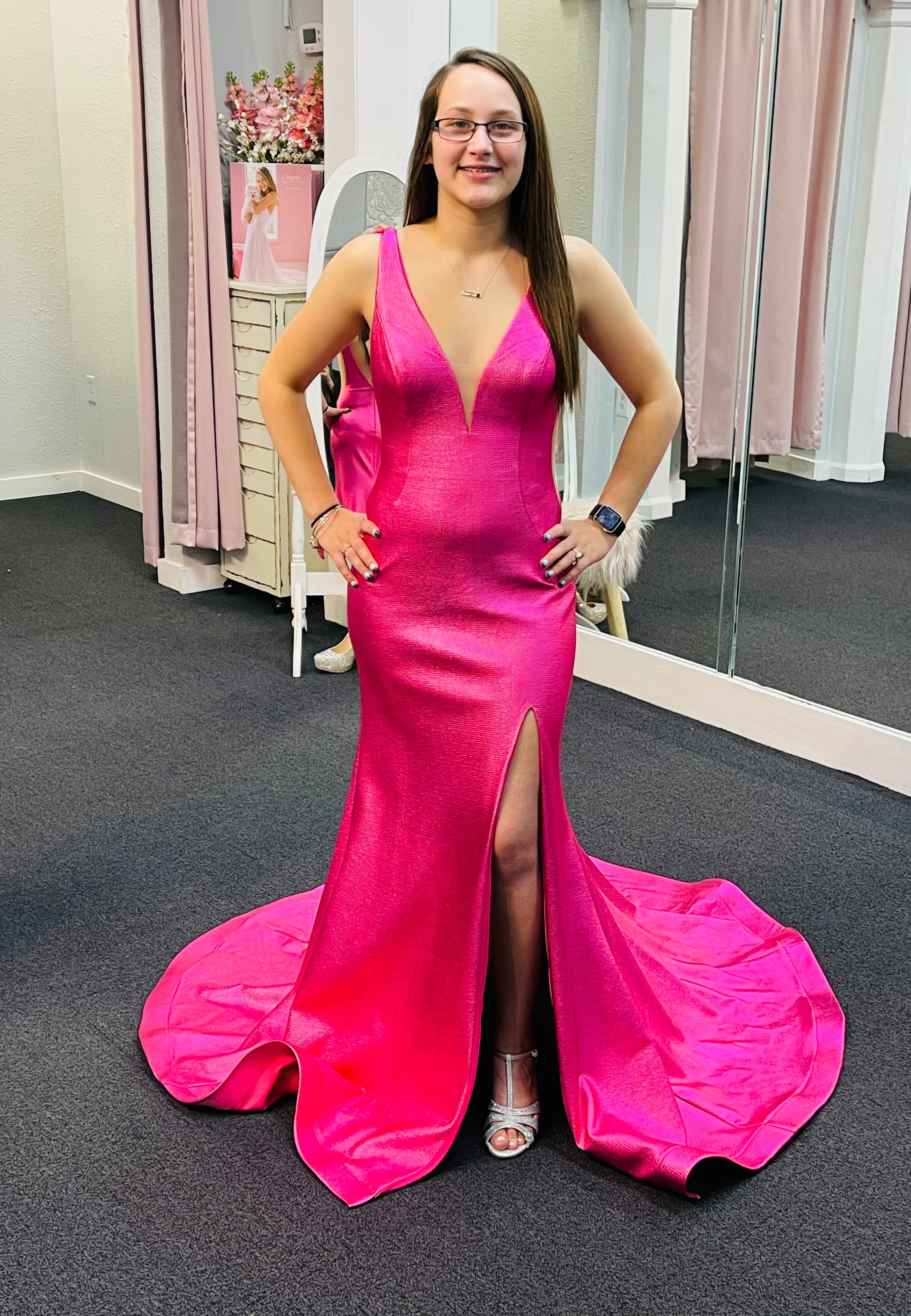 Jovani 06125 is a gorgeous Long Fitted metallic shimmer Formal Evening Gown. Plunging Deep V Neckline with an open V Back. Fit & Flare silhouette with s slit in the thigh and a lush trumpet skirt with Gorgeous sweeping train. Sheer side panels with mesh insert.  Hot Pink  Size 6