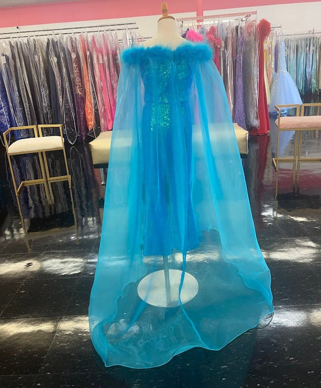 Marc Defang 8099K is a KIDS long pageant formal wear jumpsuit that is made of sequins and has off the shoulder straps.  The straps are attached to a cape with feathers at the shoulders.  Wow the crowd at your next pageant.  Available colors:  Pink, Turquoise, White, Black, Royal  Available sizes:  4,5,6,7,8,9,10,11,12,13,14   Please allow 30 Days for Delivery or a rush fee is available!