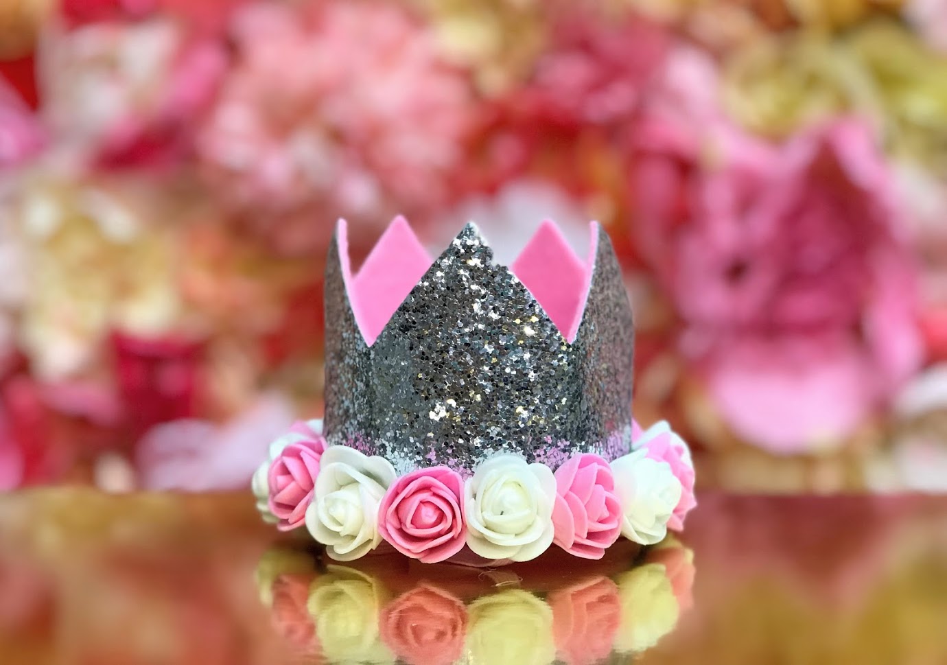 Sweet Wink - The Silver Flower Crown is the perfect addition to any birthday party or everyday dress up! Since this crown does not have a number on it, it can be worn for multiple occasions. Makes a great birthday present for any little girl in your life! Item description:  Silver glitter crown Pink and ivory flowers trim the base of the crown Light pink felt lining inside the crown and on the bottom of the crown to ensure comfort and softness on the child's head Light pink elastic to secure crown to child'