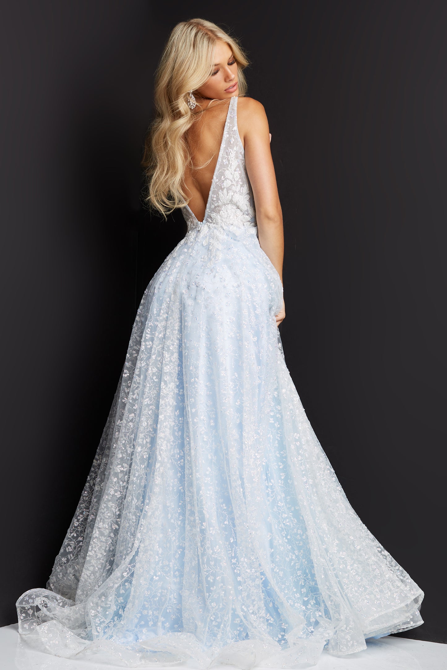 JVN08421 This JVN by Jovani prom dress is covered in floral lace with sequin embellishments to add sparkle.  The evening gown is an A line with a train and features a plunging V neckline with sheer mesh insert.  It has a low V back and a high side slit. 