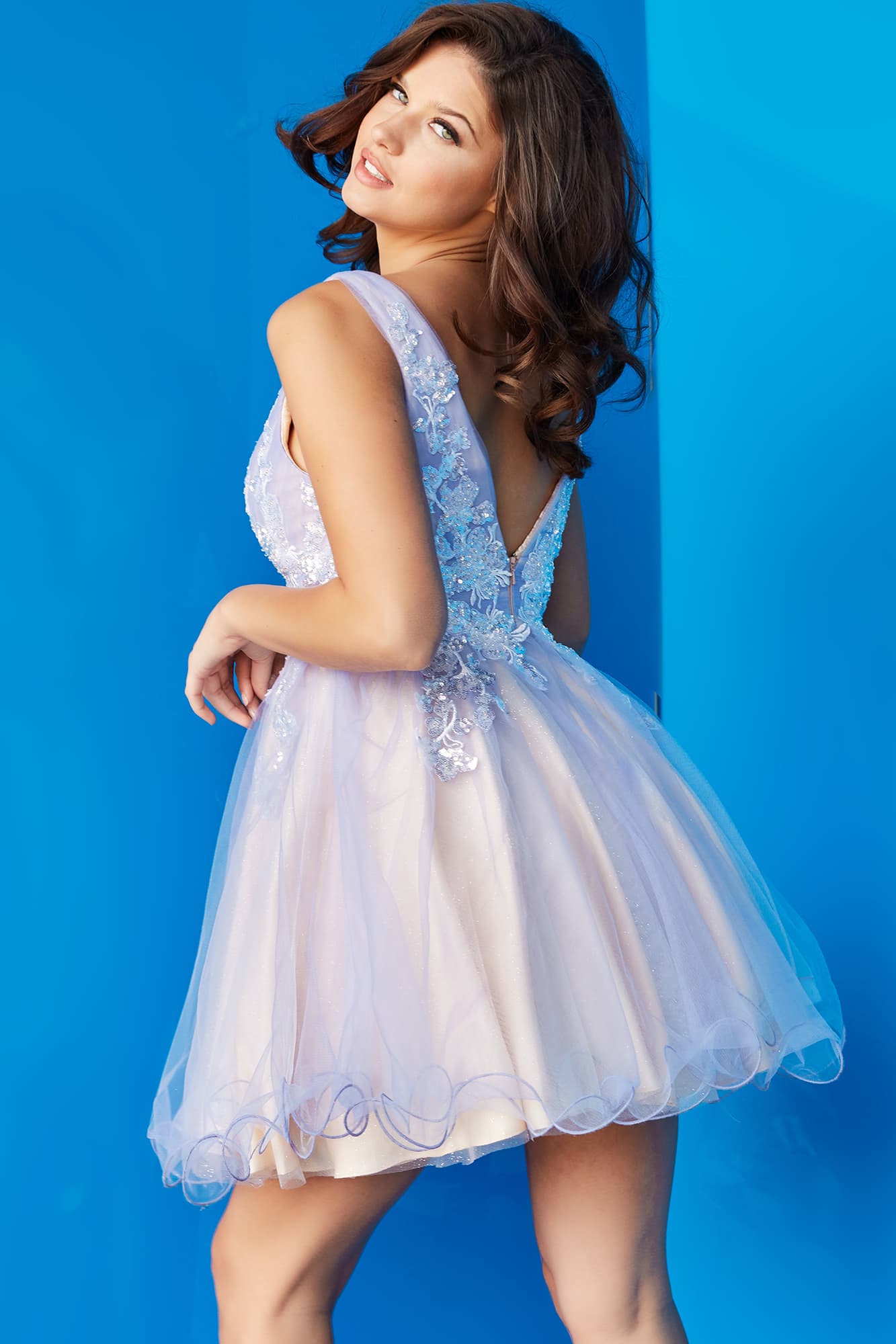 Jovani JVN22516  This JVN by Jovani lavender short dress features an A line silhouette in tulle over glitter net, with a plunging neckline, low V-back, and wired hem. Sequin lace appliques stretch over the ruched bodice and skirt.   Colors:  Lavender, Light Pink
