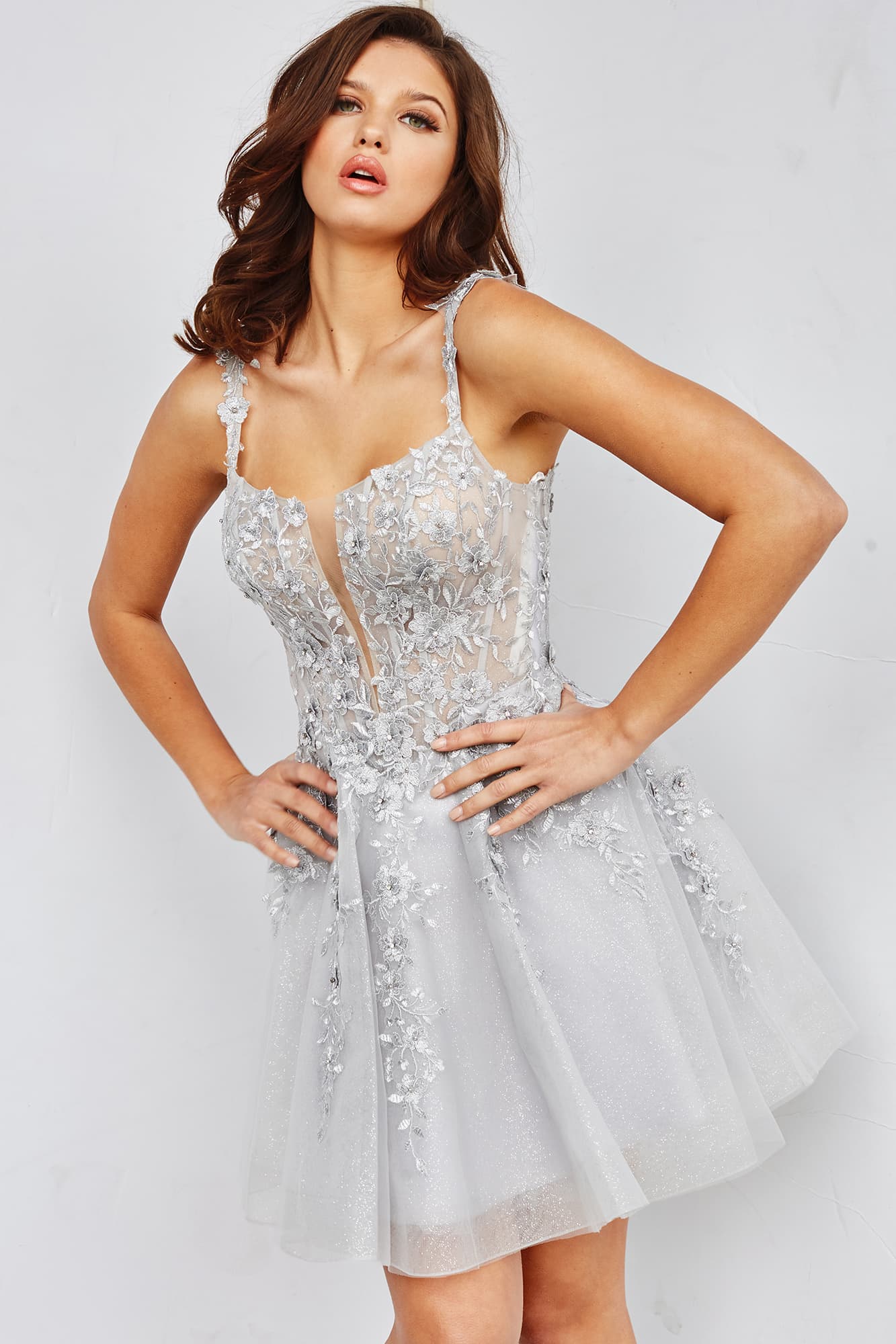 Jovani JVN22520  This JVN by Jovani homecoming dress features a sheer lace corset bodice, scoop neckline with an illusion plunging V panel, spaghetti straps and a scoop back. Beaded floral appliques richly embellish this glitter tulle A-line dress, finished with a gorgeously flared tulle skirt.