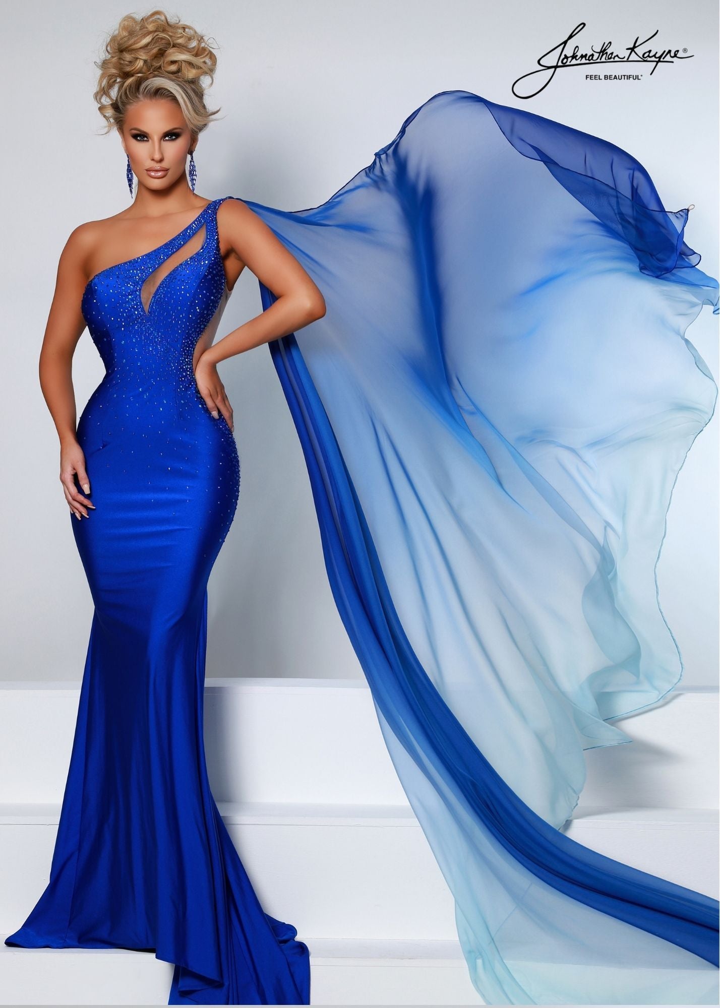 Johnathan Kayne 2516 Long Fitted Crystal embellished jersey One Shoulder Formal Pageant Dress with a detachable Ombre flowing chiffon Cape. This Gown features a keyhole cutout neckline and sheer cutout side corset back.   Sizes: 00, 0, 2, 4, 6, 8, 10, 12, 14, 16  Colors: Black, Purple, Red, Royal