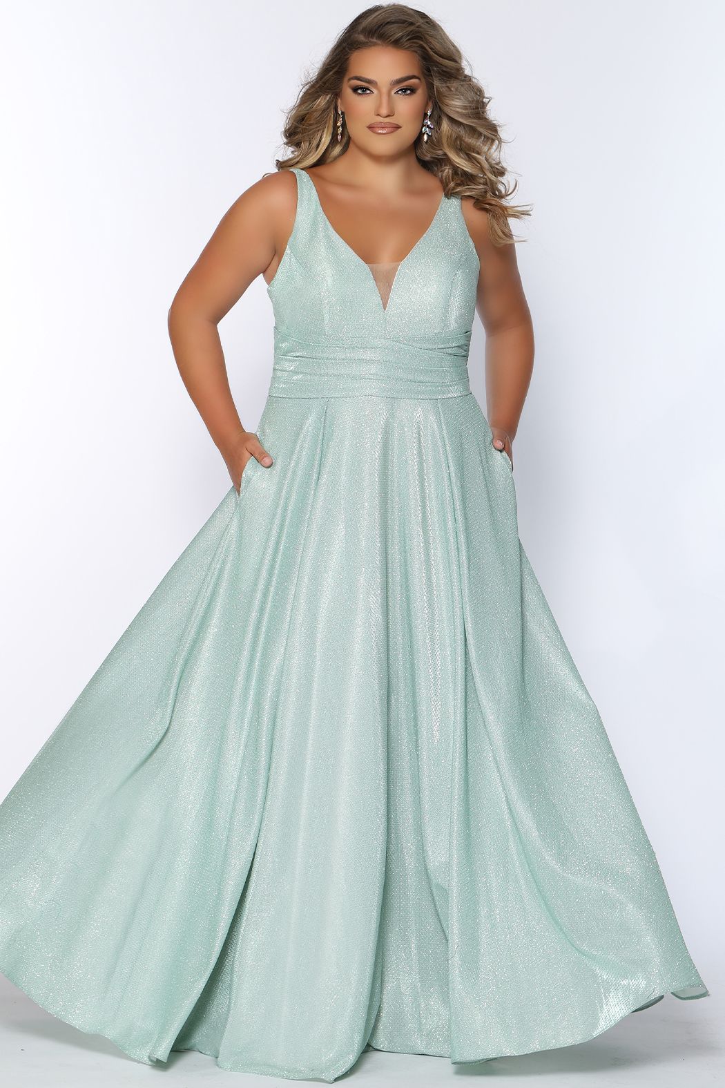 Sydney's Closet SC7324 Shimmer in a sweet metallic gown! These trending colors for Prom 2022 are perfect in Capri, Orchid, and Sage, with a knit fabric that will glide across your body, and the dance floor. It’s a classic a line v neck style, pumped up with fashion details including a pleated waistline and folds in the skirt. Must-have additions of bra-friendly straps and pockets! SC 7324
