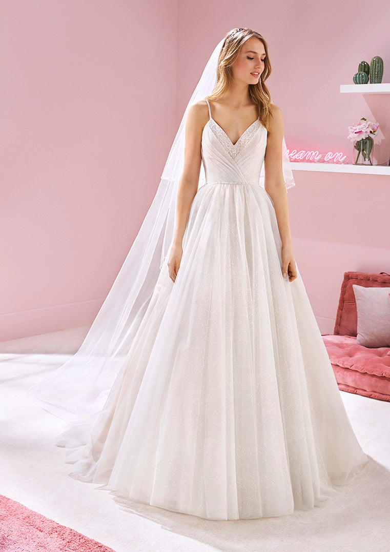 Pronovias White One Bridal NICKI  Princess gown crafted in all-over, glitter tulle with a V-neckline of beaded embroidery, a beautiful bodice of asymmetrical drapery, and a voluminous, layered skirt.  Available: US SIZE 16  Color: Off White/Light Beige  IN STOCK FOR IMMEDIATE DELIVERY!   