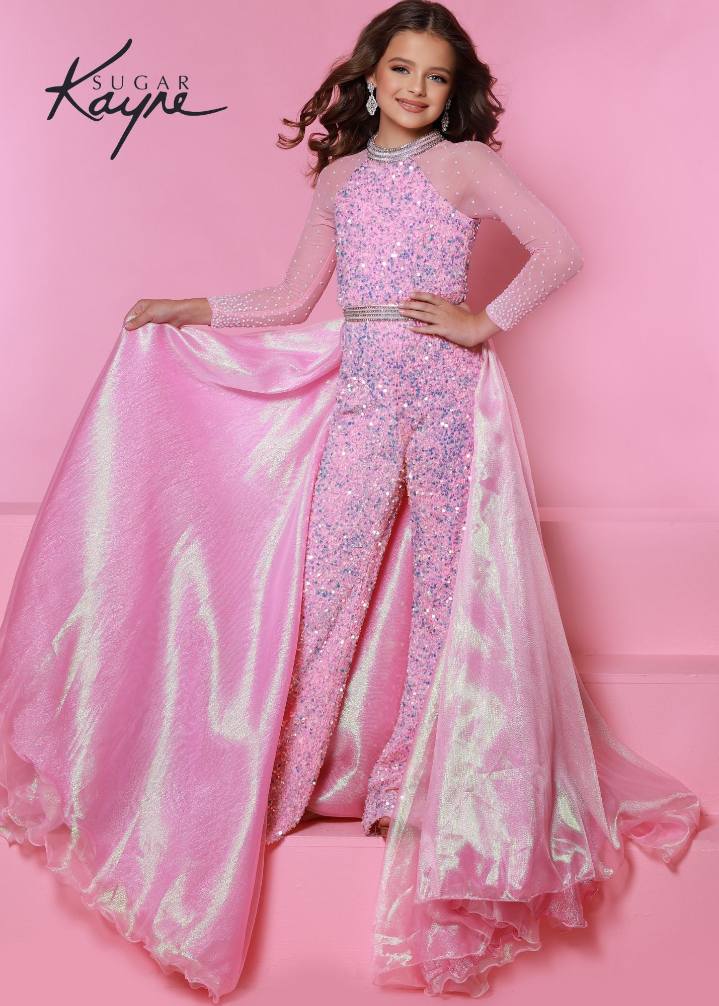 Sugar Kayne C104 by Johnathan Kayne is a Fun & Convertible Pageant Style. This is a Comfortable Stretch Velvet - Sequin Embellished Long Formal Jumpsuit. Featuring a high Crystal Embellished neckline and sheer long sleeves embellished with rhinestones. Detachable Metallic Shimmer Organza Long Overskirt Has rows of Crystal Rhinestone matching the neckline. Fun Fashion cotton candy pink