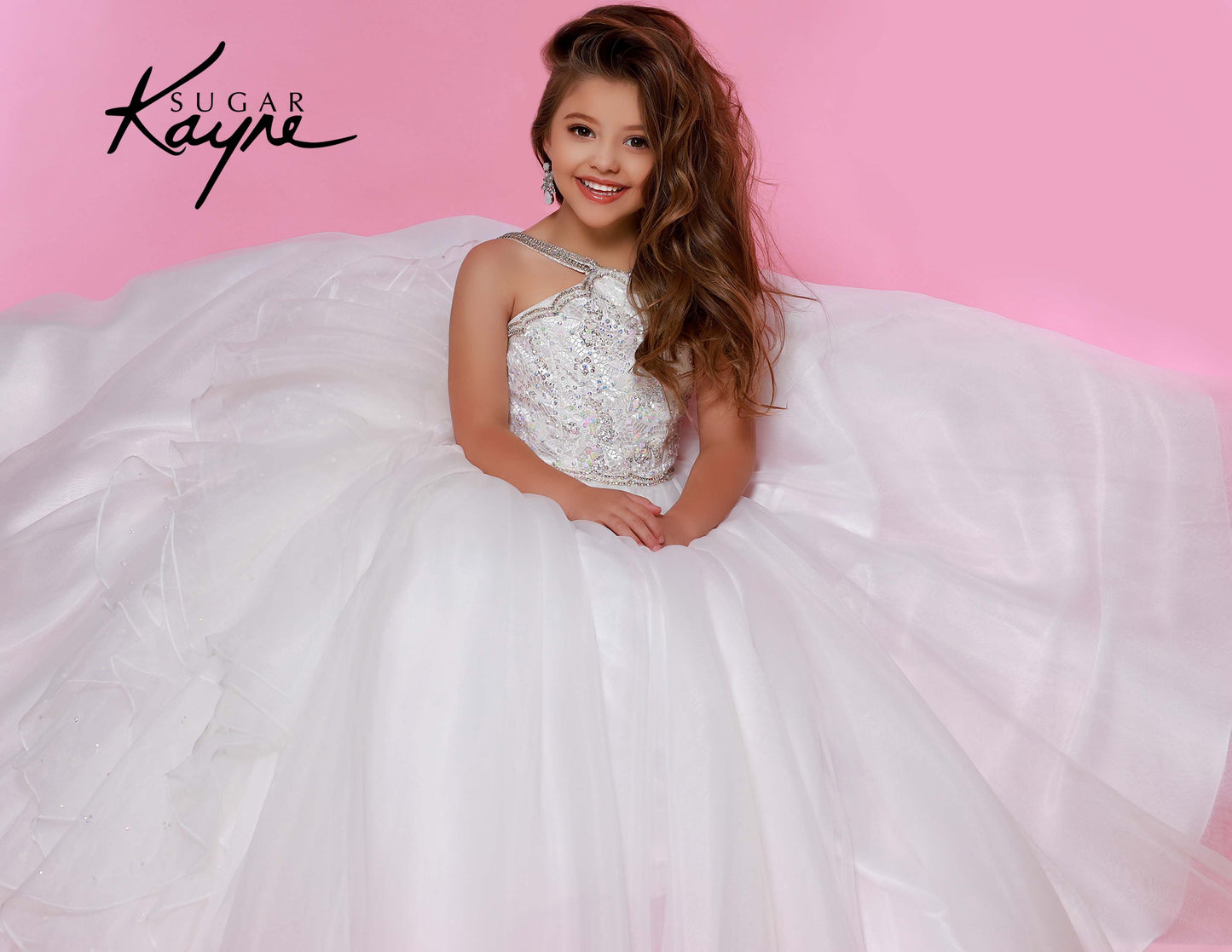 Sugar Kayne C143 Girls and Preteens Pageant Dress.  This is a beautiful flowy organza pageant gown with embellished high neckline.  This dress features an organza ruffle that flows down the back of the dress white