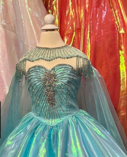 This Sugar Kayne C334 Pageant Dress features a luxurious iridescent organza long ball gown skirt and a crystal sweetheart neckline, designed specifically for girls and preteens. An embellished cape with fringe completes the style.  Sizes:  2, 4, 6, 8, 10, 12, 14, 16  Colors  Mermaid Blue, Papaya, Unicorn