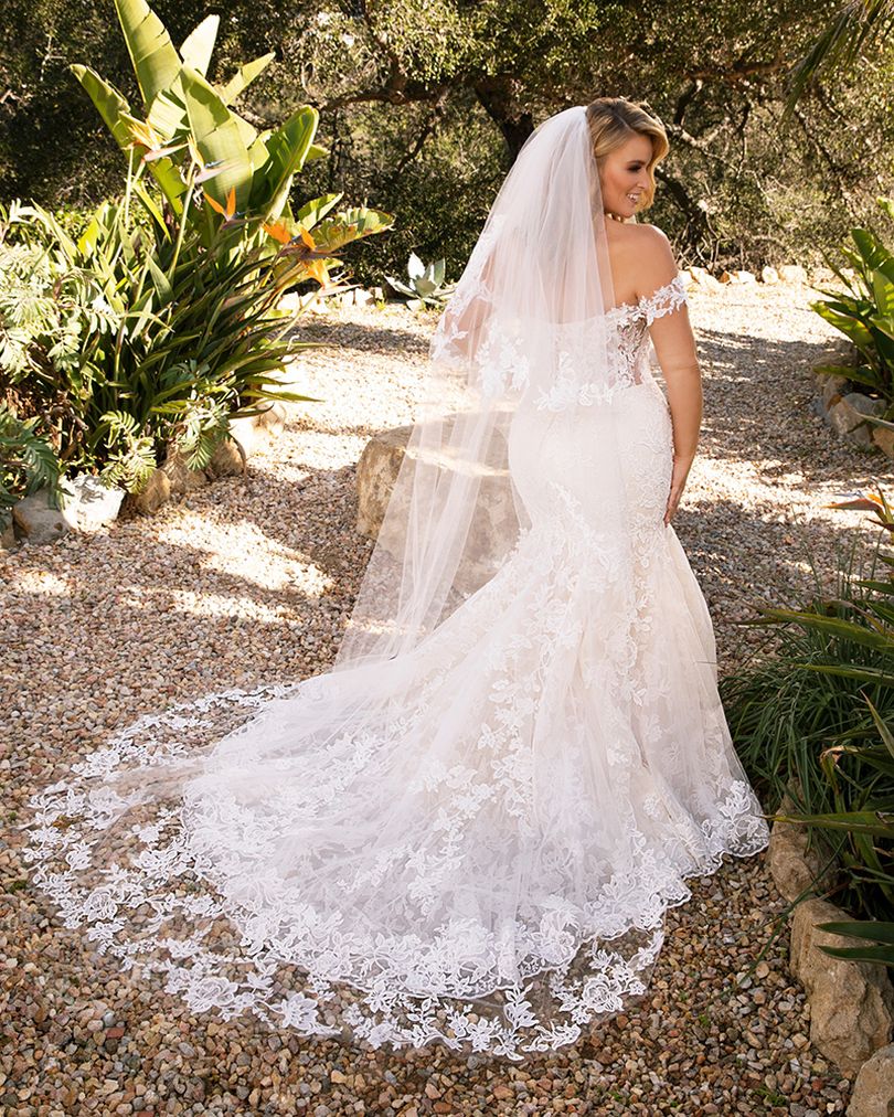 Style 2376 KARINA by Casablanca Bridal is a glamorous twist on the classic lace wedding dress. Off-shoulder sleeves transition into a classic sweetheart neckline, while floral lace swirls all throughout the fit-and-flare silhouette. The illusion back, lined with a row of subtle crystal buttons, transitions flawlessly into a gently scalloped train. A matching, two-tier cathedral length veil is available for the bride who wants to make an extra remarkable impact.  Size: 10, 14, 20  Ivory/Nude/Ivory/Silver