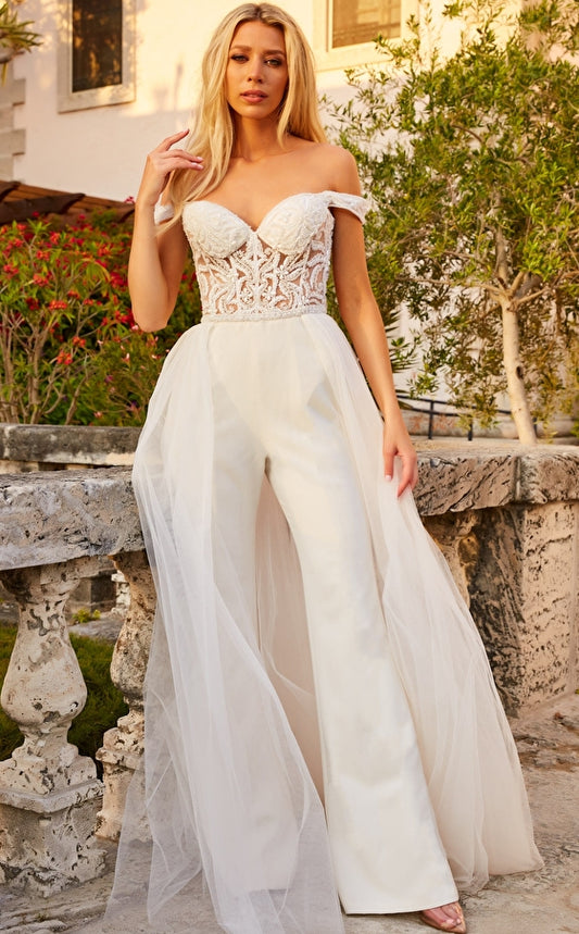 Jovani Bridal JB06507 Sheer Off the Shoulder Wedding Dress Jumpsuit Overskirt Beaded Bridal This Jovani JB06507 off white bridal jumpsuit features a sheer corset bodice with intricate tonal beadwork, crowned with an off-the-shoulder sweetheart neckline. A beaded waistband tops the slim-flare pants, finished with a gathered tulle overskirt.  Available Sizes: 00-24  Available Colors: Off White
