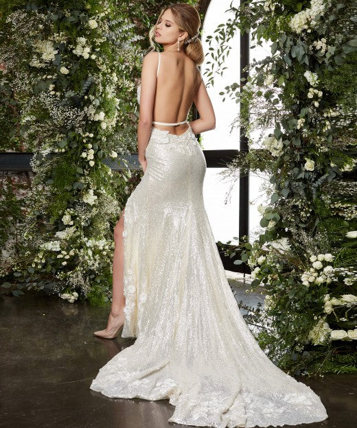 Jovani Bridal JB03592 cream bridal gown features a slim silhouette with a deep plunging neckline, spaghetti straps and a single-strap open back. Three-dimensional floral appliques embellish this sequin wedding dress, finished with a thigh-high slit and a chapel train. Sequin Floral Lace Backless Wedding Dress Slit Train Fitted  Available Sizes: 00-24  Available Colors: Cream