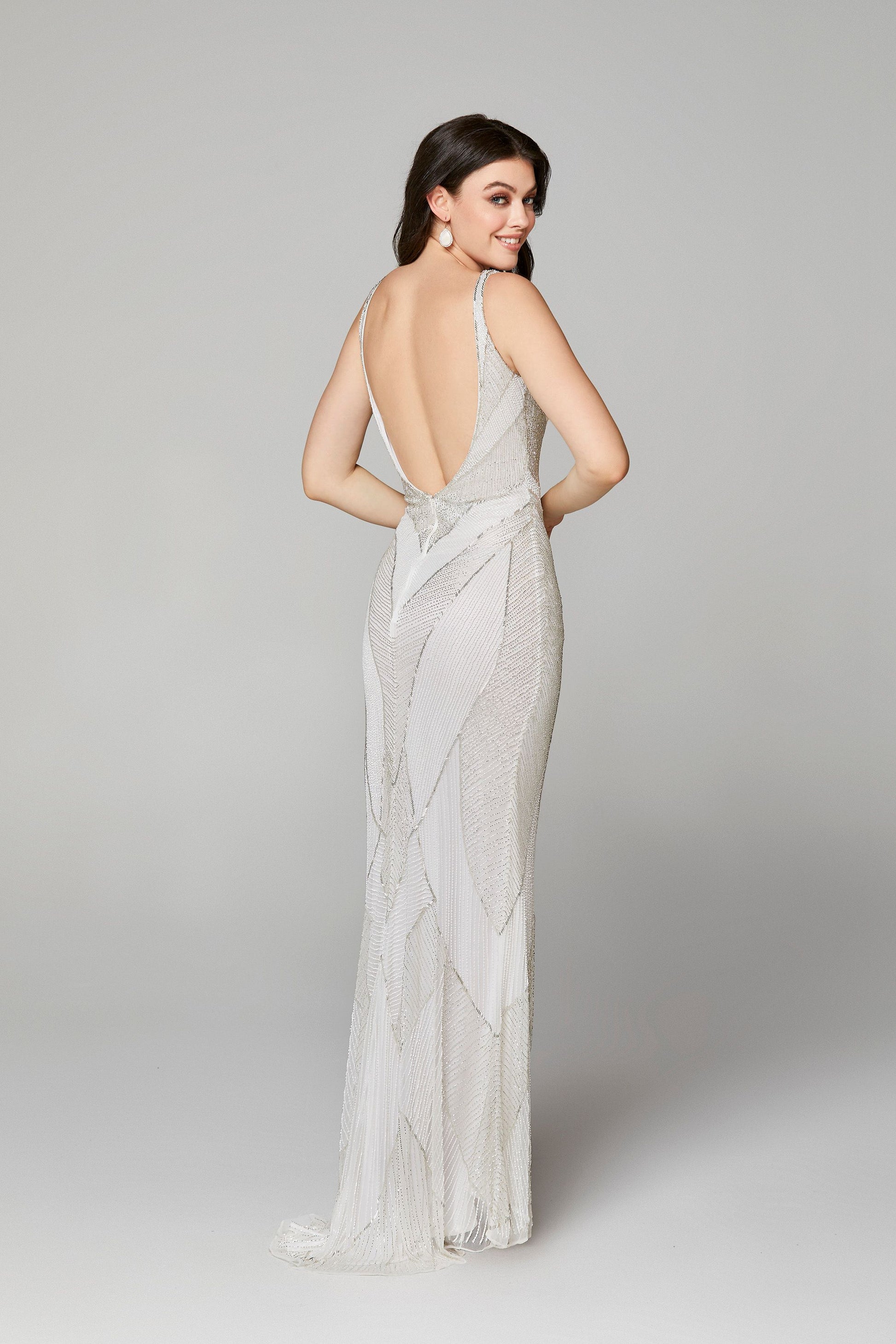 Primavera Couture 3629 is a long fitted formal evening gown. Featuring a V neckline and an open back. This backless prom dress has Flattering Geometric Beading to accentuate any figure! Sweeping train falling behind the skirt.  Available Sizes: 00,0,2,4,6,8,10,12,14,16,18  Available Colors: Black/Silver, Ivory, Midnight