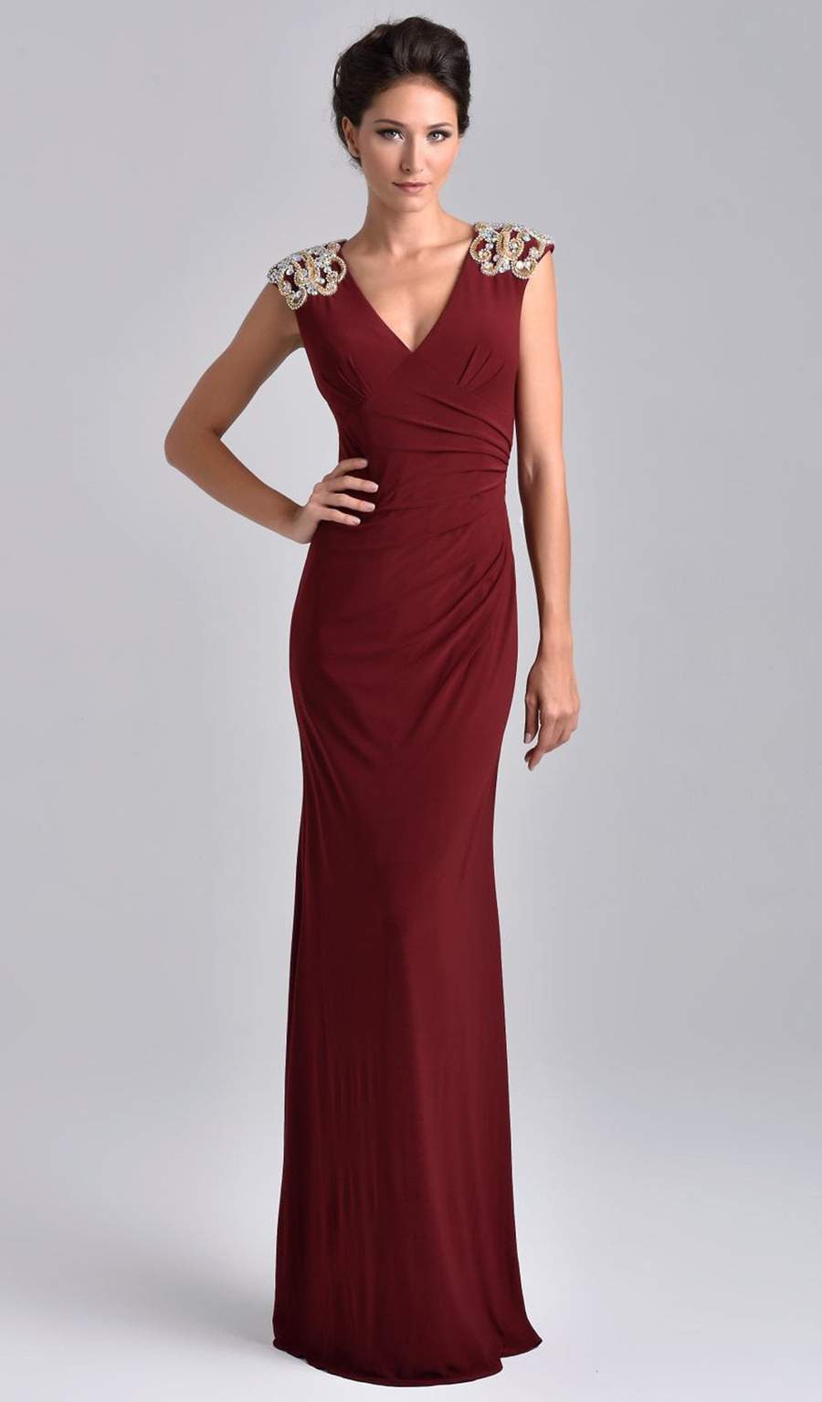 Nina Canacci M206 Stand tall and straight in Nina Canacci M206. This refined long gown features a deep V-neckline and cap sleeves. Delicate patterns of compressed beads patches the shoulders. Rouge forms on the side and dramatically scatters sideways leaving a semi-fitted silhouette look. The long skirt drops perfectly and nearly touches the floor leaving an elegant hemline. Available Sizes: 6, 8, 10  Available Colors: Burgundy, Navy, Taupe