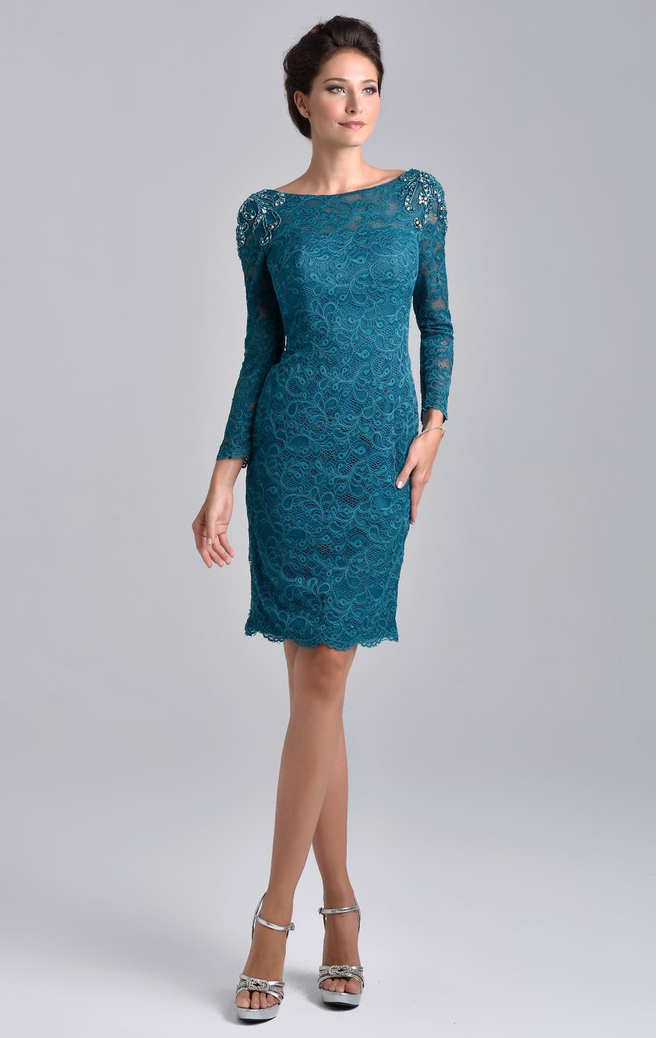 Nina Canacci M208 is a short fitted lace knee length cocktail dress. Sheer High lace neckline with long sleeves. beading, Crystal Rhinestones & Embellishments adorn the shoulder on this great mother of the bride/groom style. Available Sizes: 6, 8, 10  Available Colors: Brown