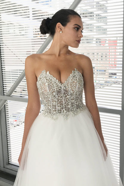 Johnathan Kayne Bridal B200 is a stunning fully crystal embellished Sheer bodice with peak pointes. Lace up corset back closure. A Line Ballgown Wedding Dress & Bridal Gown with a lush Tulle skirt. Jaw Dropping Glam Bridal Style!  Available Sizes: 00,0,2,4,6,8,10,12,14,16  Available Colors: Ivory