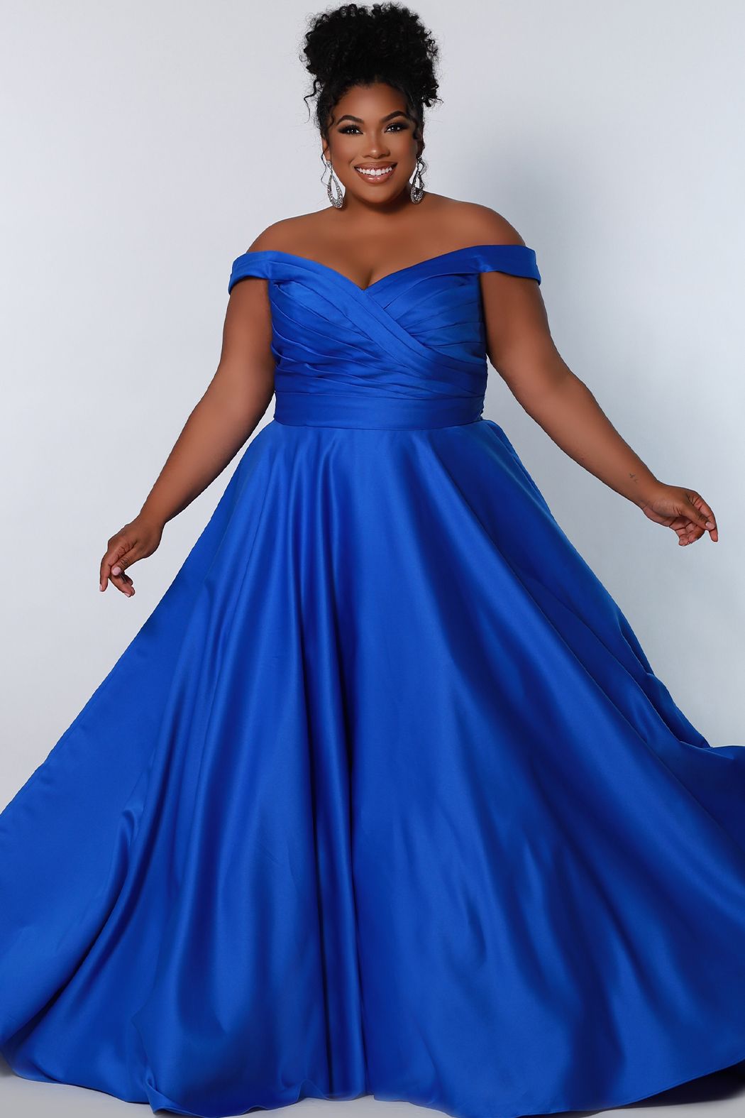 Sydney's Closet SC7321 This is an a line plus size prom dress with a pleated bodice and a v-neckline and v-back. Off-the-shoulder straps accompany elastic bands for full dancing ability! The full crinoline a line skirt flatters your natural waistline, and is made complete with a party must-have, pockets.